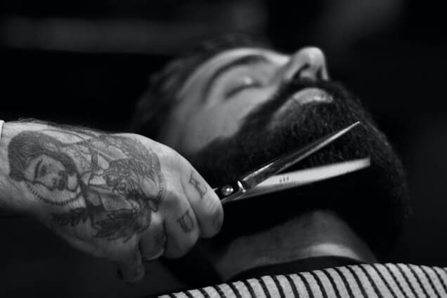 A barber shaping a client’s beard at Rob’s Barber Shop